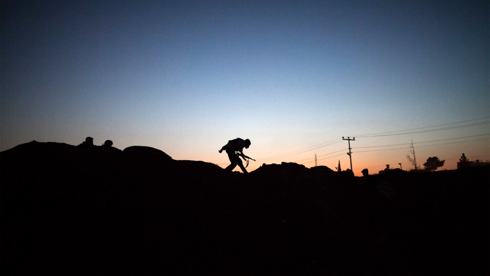 The silhouette of an armed fighter of the Committees for the Protection of the Kurdish People (YPG) is seen as runs to take position along the front line on October 16, 2013 in the Syrian town of Ras al-Ain, close to the Turkish border.