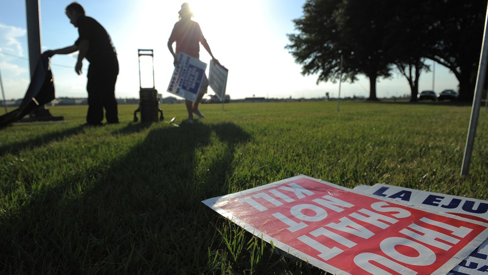 People opposed to the death penalty pick up signs as they gathered to demonstrate against the execution of John Ruthell Henry near the Florida State Prison on June 18, 2014 in Raiford, FL. (Photo by Matt McClain/The Washington Post/Getty)