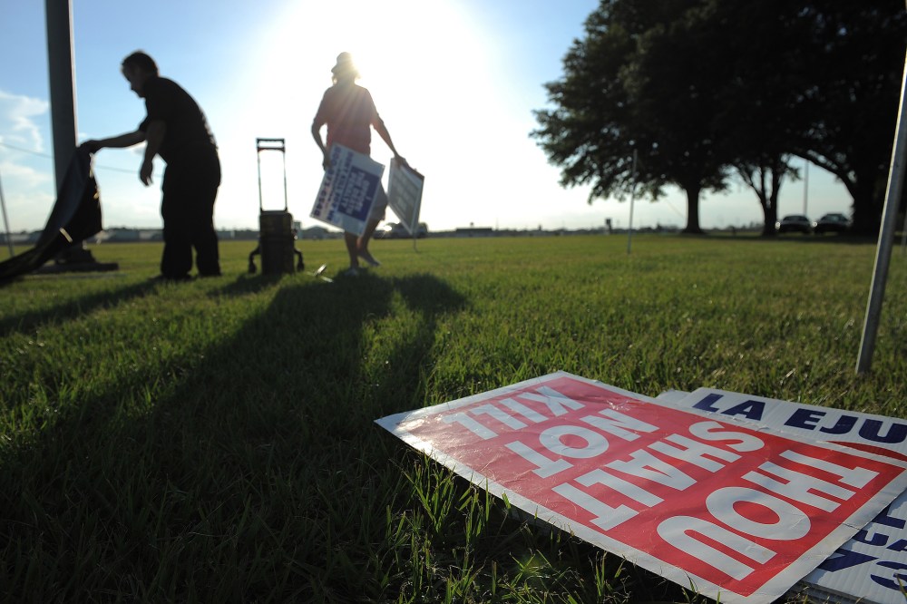 People opposed to the death penalty pick up signs as they gathered to demonstrate against the execution of John Ruthell Henry near the Florida State Prison on June 18, 2014 in Raiford, FL. (Photo by Matt McClain/The Washington Post/Getty)