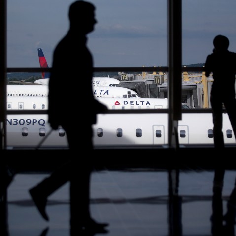 The silhouettes of a travelers are seen walking past Delta Air Lines airplanes parked at gates of Ronald Reagan National Airport in Washington, D.C. (Photo by Andrew Harrer/Bloomberg/Getty)