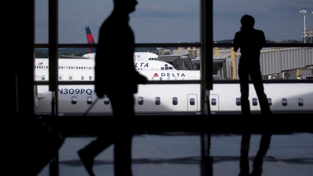 The silhouettes of a travelers are seen walking past Delta Air Lines airplanes parked at gates of Ronald Reagan National Airport in Washington, D.C. (Photo by Andrew Harrer/Bloomberg/Getty)