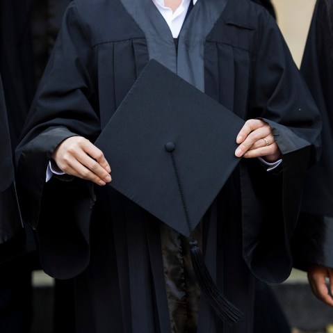 A graduate holds her cap before celebrating her graduation. (Photo by Jens Schlueter/Getty)