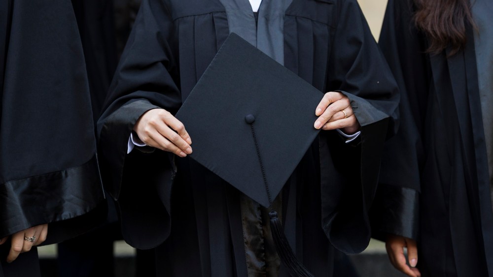 A graduate holds her cap before celebrating her graduation. (Photo by Jens Schlueter/Getty)