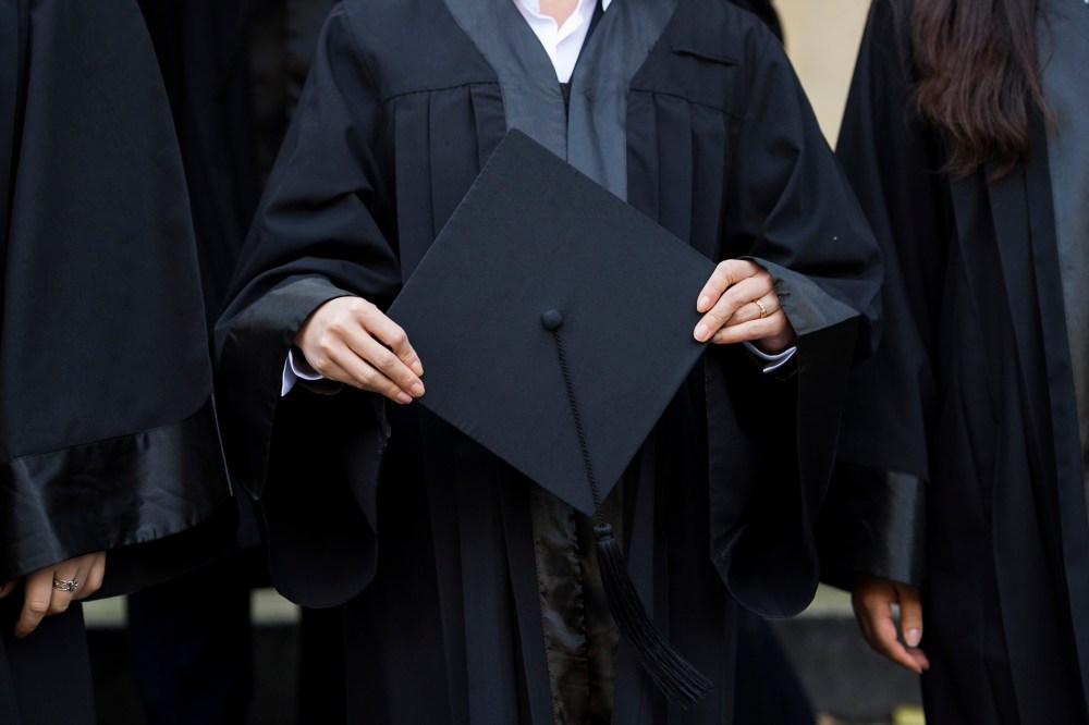 A graduate holds her cap before celebrating her graduation. (Photo by Jens Schlueter/Getty)