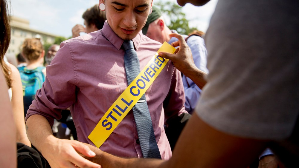 Demonstrator Ron Busby, with Center for American Progress, right, places a "Still Covered" sticker onto Kory Masen after the U.S. Supreme Court ruled 6-3 to save Obamacare tax subsidies, June 25, 2015. (Photo by Andrew Harrer/Bloomberg/Getty)