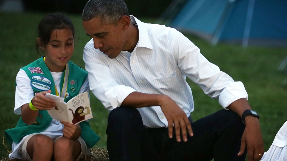 Daphnye Shell reads a book with U.S. President Barack Obama during a campfire songs session at the first-ever White House Campout (Photo by Alex Wong/Getty).