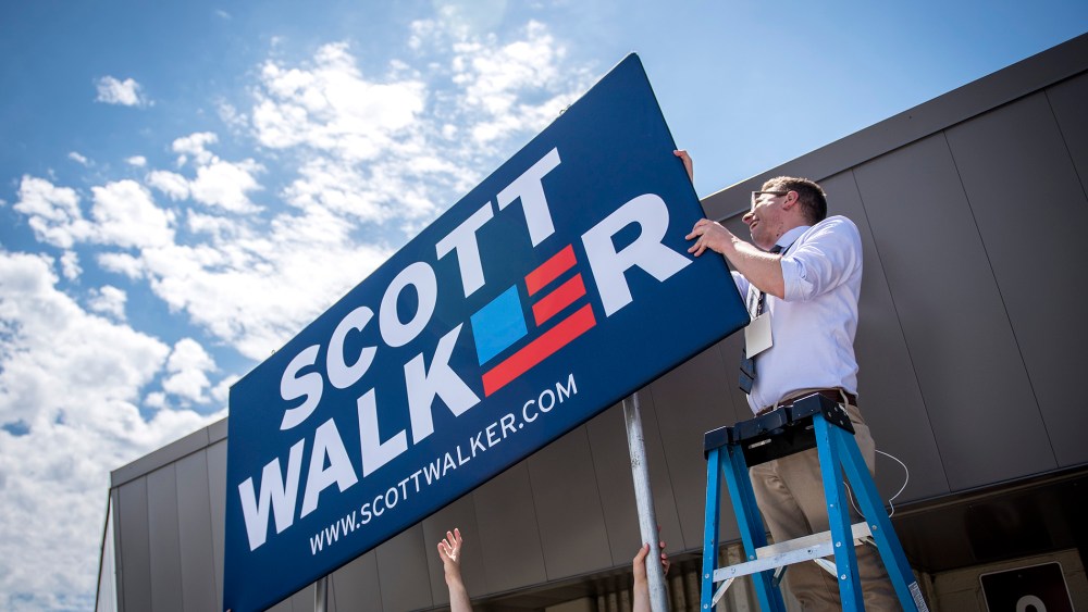 Campaign staff members for Scott Walker, governor of Wisconsin, install a sign in front of the Waukesha County Expo Center in Waukesha, Wis. on July 13, 2015. (Photo by Christopher Dilts/Bloomberg/Getty)