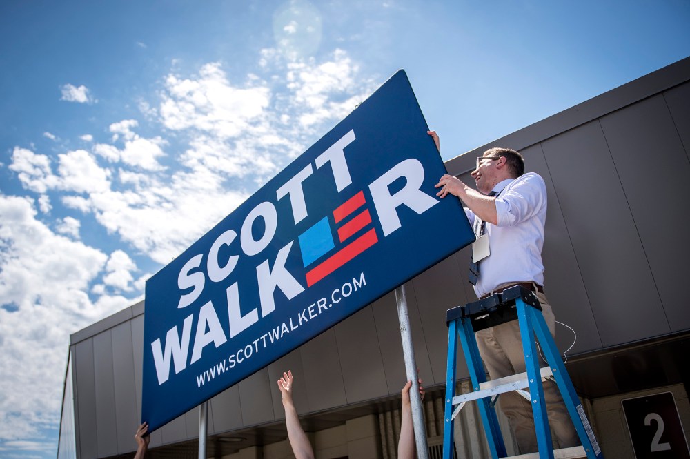 Campaign staff members for Scott Walker, governor of Wisconsin, install a sign in front of the Waukesha County Expo Center in Waukesha, Wis. on July 13, 2015. (Photo by Christopher Dilts/Bloomberg/Getty)