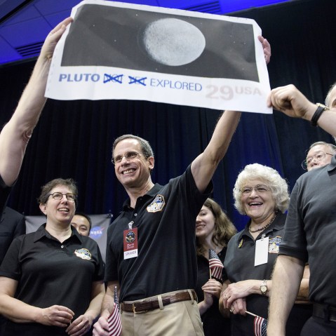 Dr. Allan Stern and others hold up their suggestion for a modified US Post Office stamp of Pluto at the Johns Hopkins University Applied Physics Laboratory on July 14, 2015 in Laurel, Md. (Photo by Brendan Smialowski/AFP/Getty)