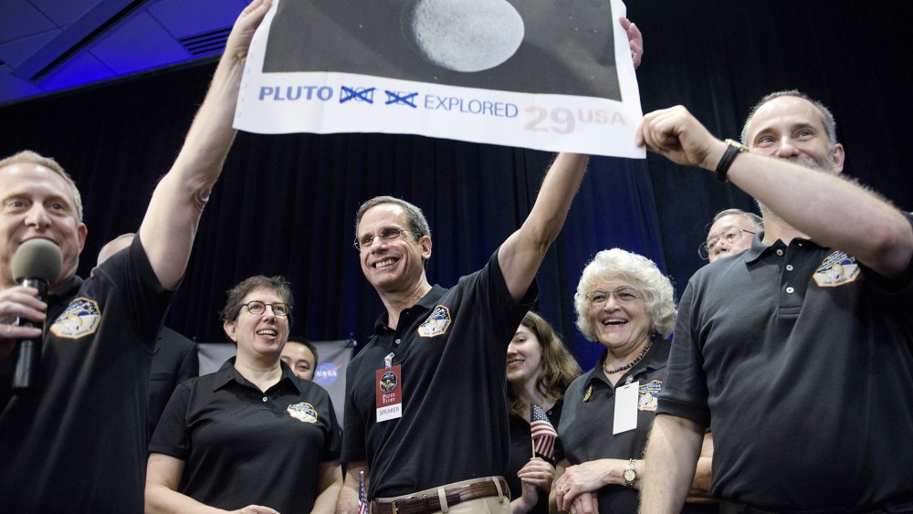 Dr. Allan Stern and others hold up their suggestion for a modified US Post Office stamp of Pluto at the Johns Hopkins University Applied Physics Laboratory on July 14, 2015 in Laurel, Md. (Photo by Brendan Smialowski/AFP/Getty)