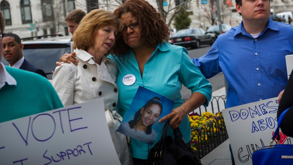 Relatives of victims of notable shootings comfort one another during a protest outside the National Shooting Sports Foundation's annual Congressional Fly-In fundraising dinner April 2, 2014, in Washington, DC. (Photo by Rod Lamkey/Getty)