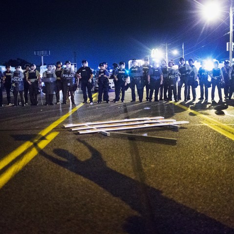 Police stand guard as demonstrators, marking the one-year anniversary of the shooting of Michael Brown, protest along West Florrisant Street on Aug. 10, 2015 in Ferguson, Mo. (Photo by Scott Olson/Getty)