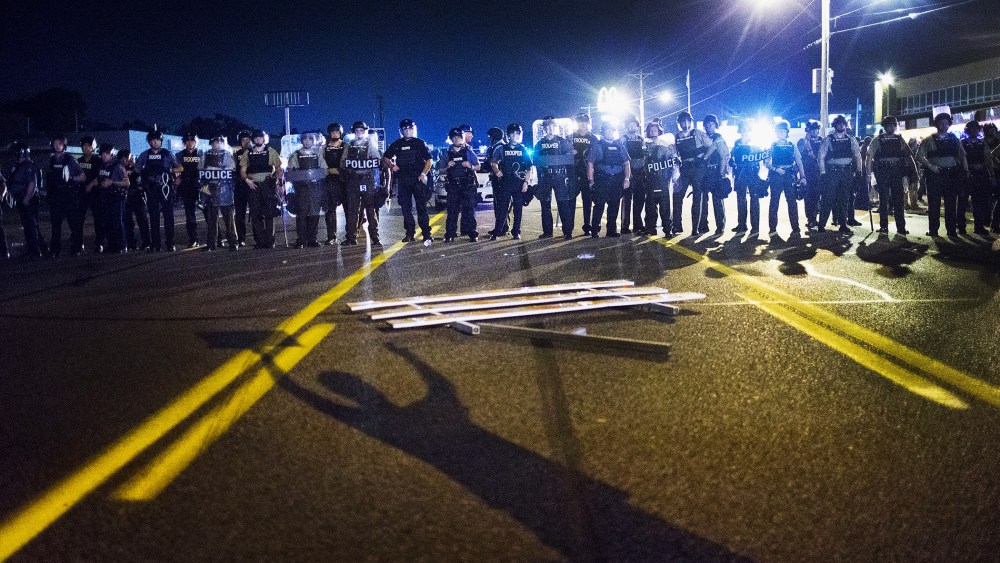 Police stand guard as demonstrators, marking the one-year anniversary of the shooting of Michael Brown, protest along West Florrisant Street on Aug. 10, 2015 in Ferguson, Mo. (Photo by Scott Olson/Getty)