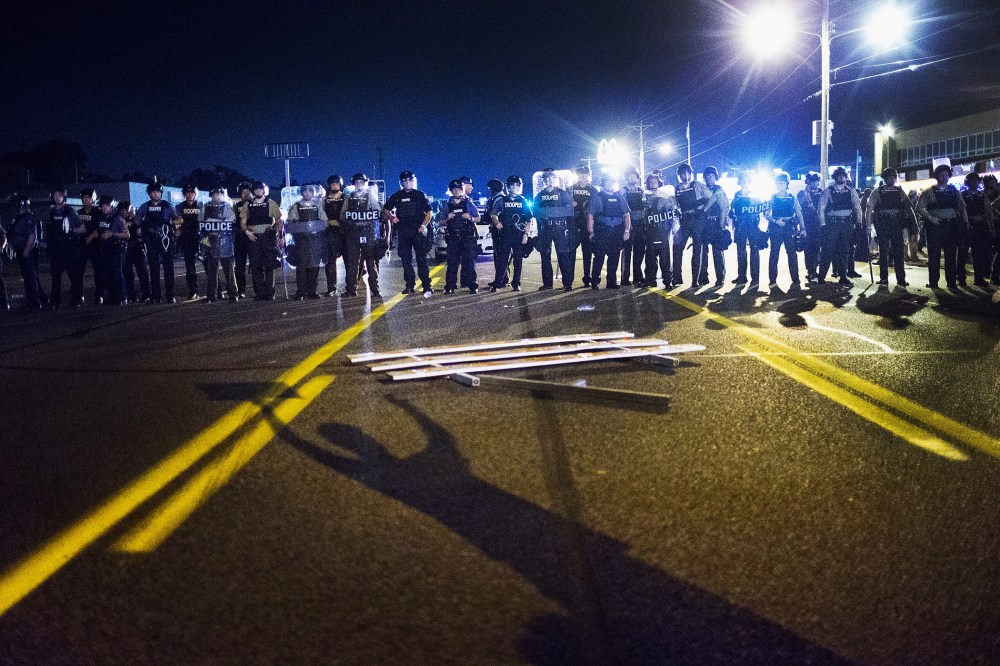 Police stand guard as demonstrators, marking the one-year anniversary of the shooting of Michael Brown, protest along West Florrisant Street on Aug. 10, 2015 in Ferguson, Mo. (Photo by Scott Olson/Getty)