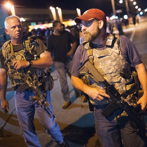 Oath Keepers carrying rifles walk along West Florissant Street as demonstrators protest on Aug. 10, 2015 in Ferguson, Mo. (Photo by Scott Olson/Getty)