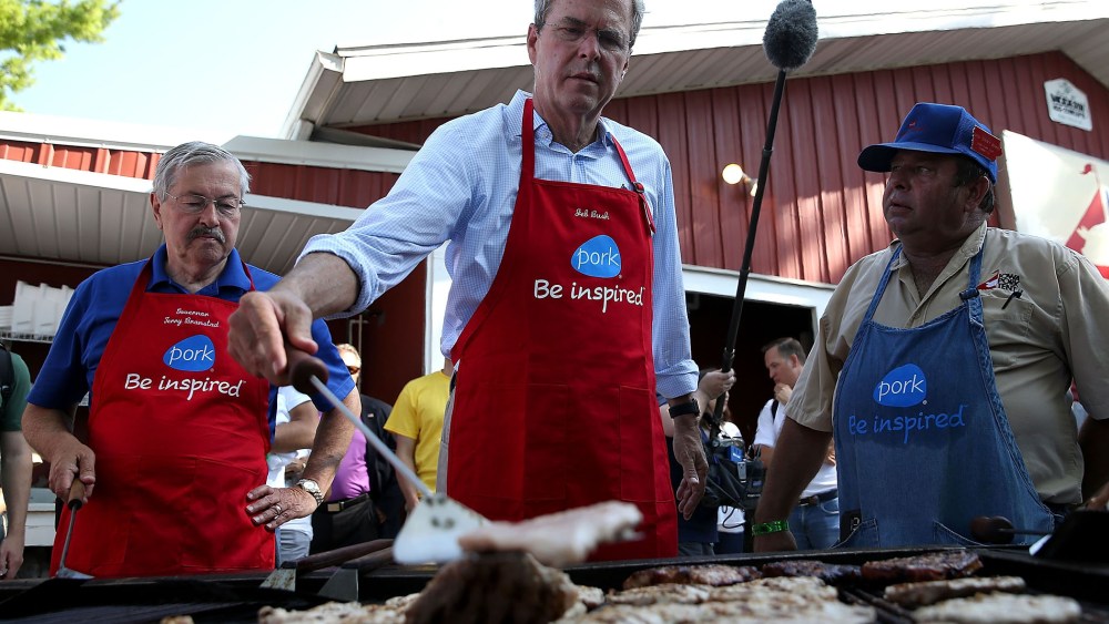 Republican presidential hopeful and former Florida Gov. Jeb Bush (C) flips a pork chop on a grill at the Iowa Pork Tent (Photo by Justin Sullivan/Getty).