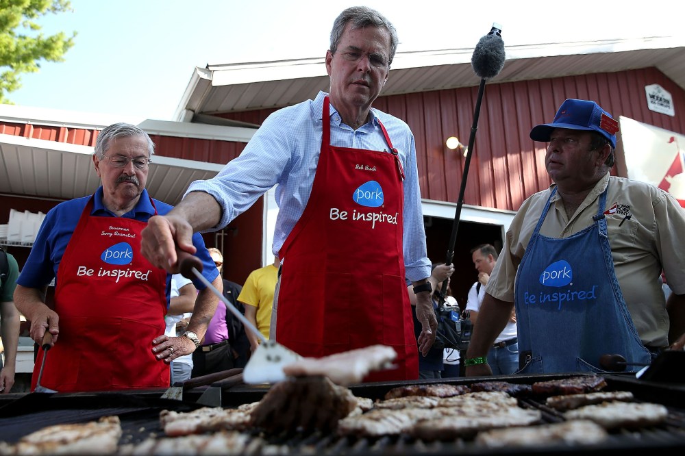 Republican presidential hopeful and former Florida Gov. Jeb Bush (C) flips a pork chop on a grill at the Iowa Pork Tent (Photo by Justin Sullivan/Getty).