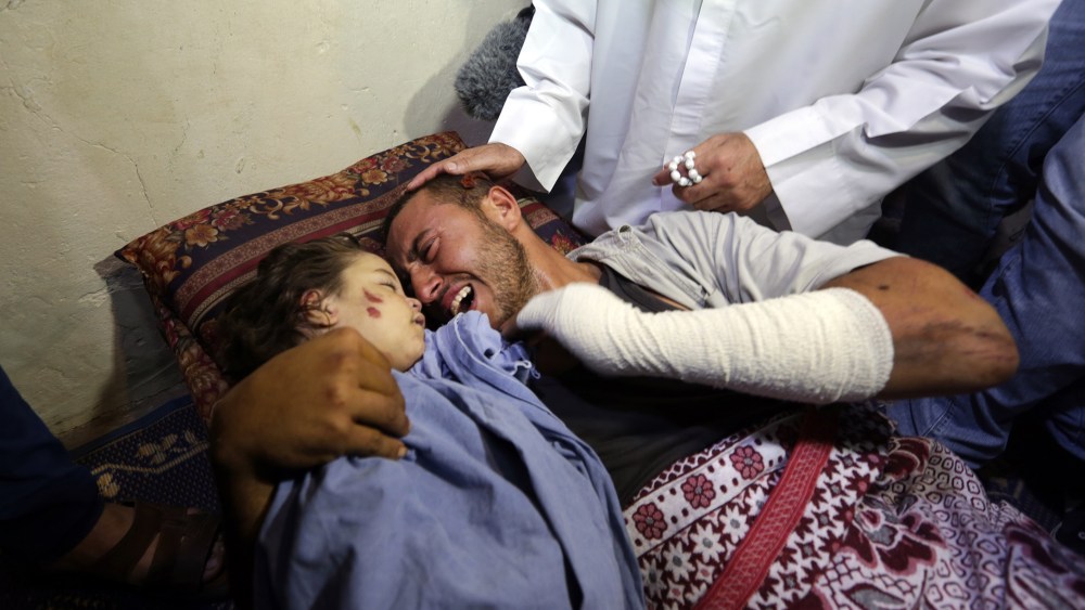 Palestinian father Yehya Hasan mourns while holding the body of his daughter, Rahaf, during a funeral for the toddler and her pregnant mother on Oct. 11, 2015, at the al-Nusairat refugee camp, in central Gaza Strip. (Photo by Mahmud Hams/AFP/Getty)