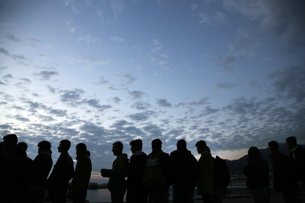 Iraqi, Syrian and Afghan refugees wait in line at dawn for a ferry to Athens after they arrived on the island of Lesbos in a raft from Turkey on Oct. 13, 2015 in Mitilini, Greece. (Photo by Spencer Platt/Getty)