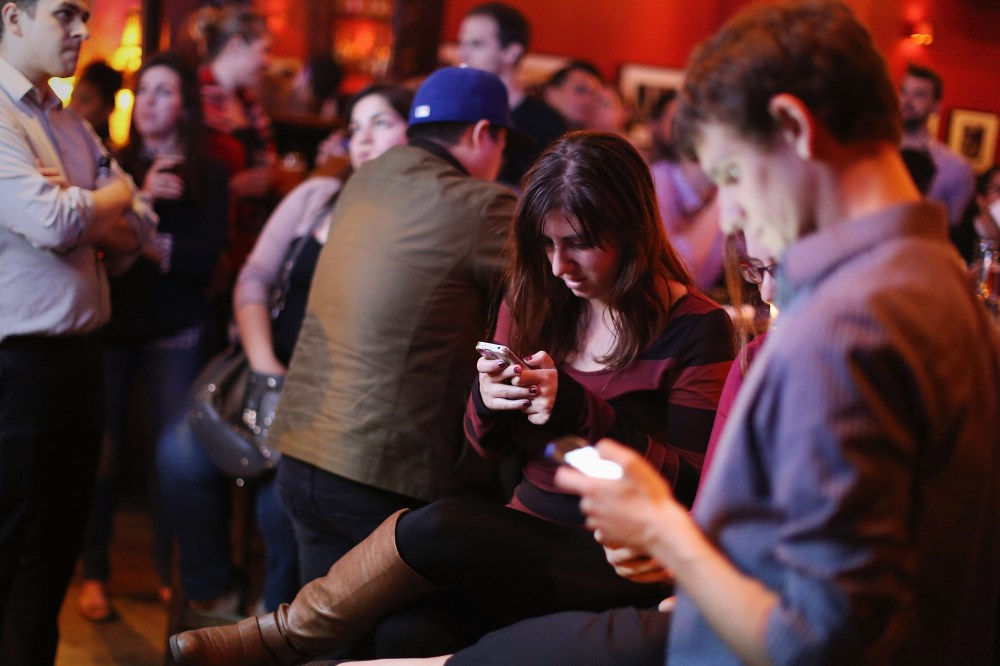 Young adults split their attention between a televised Democratic debate and using their smart phones during a watch party in Washington, DC., Oct. 13, 2015. (Photo by Chip Somodevilla/Getty)