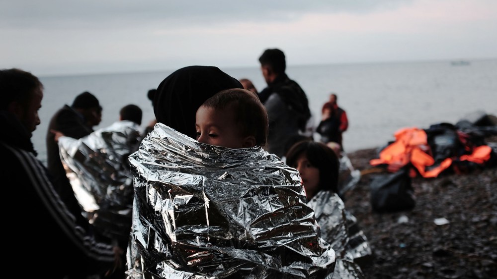 A group of migrants huddle on the beach after arriving by raft from Turkey onto the island of Lesbos on Oct. 21, 2015 in Sikaminias, Greece. (Photo by Spencer Platt/Getty)