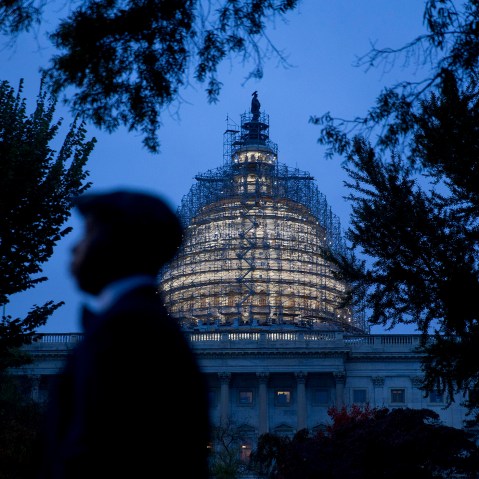 The U.S. Capitol building surrounded by scaffolding as someone walks by on Oct. 28, 2015, in Washington, D.C. (Photo by Andrew Harrer/Bloomberg/Getty)
