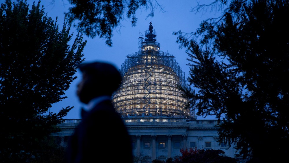 The U.S. Capitol building surrounded by scaffolding as someone walks by on Oct. 28, 2015, in Washington, D.C. (Photo by Andrew Harrer/Bloomberg/Getty)