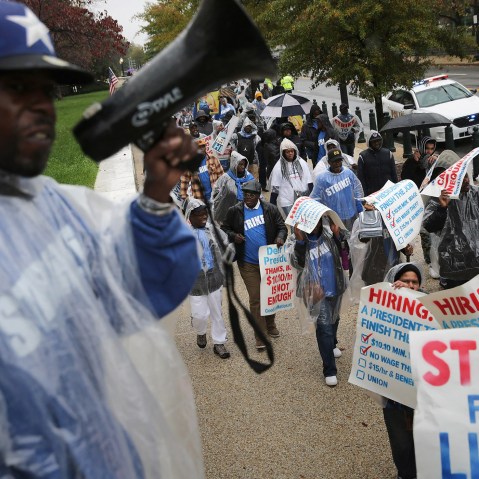 Demonstrators march along Constitution Avenue during a protest to call for higher wages for government contract workers on Capitol Hill Nov. 10, 2015 in Washington, DC. (Photo by Chip Somodevilla/Getty)