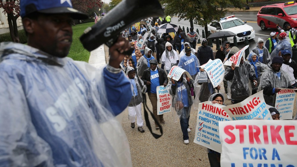 Demonstrators march along Constitution Avenue during a protest to call for higher wages for government contract workers on Capitol Hill Nov. 10, 2015 in Washington, DC. (Photo by Chip Somodevilla/Getty)