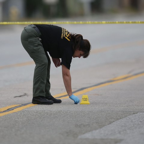 A Law enforcement officer picks up as shell casing near the Ford SUV vehicle that was the scene where suspects of the shooting at the Inland Regional Center were killed on Dec. 4, 2015 in San Bernardino, Calif. (Photo by Joe Raedle/Getty)