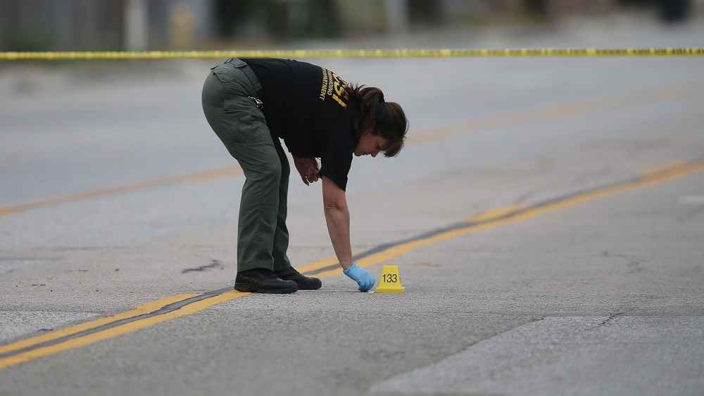 A Law enforcement officer picks up as shell casing near the Ford SUV vehicle that was the scene where suspects of the shooting at the Inland Regional Center were killed on Dec. 4, 2015 in San Bernardino, Calif. (Photo by Joe Raedle/Getty)