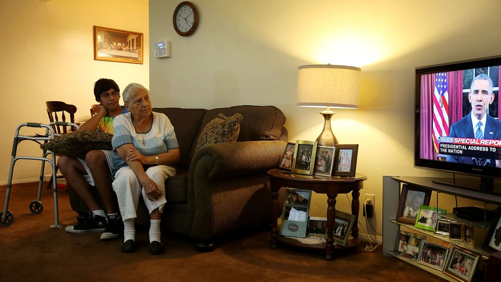 Jonathan Tovar and his grandmother Helen Medina in her house, which was hit by bullets in a gun battle between police and terror suspects, watch President Obama's address, Dec. 6, 2015 in San Bernardino, Calif. (Photo by Joe Raedle/Getty)