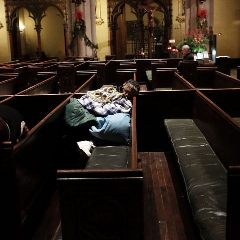 A homeless man sleeps in the warmth of a church in midtown Manhattan after a recent cold spell on Jan. 5, 2016 in New York City. (Photo by Spencer Platt/Getty)