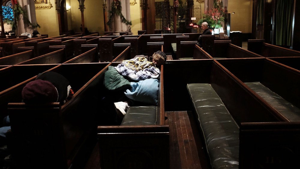 A homeless man sleeps in the warmth of a church in midtown Manhattan after a recent cold spell on Jan. 5, 2016 in New York City. (Photo by Spencer Platt/Getty)