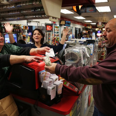 Gale Call (L) and Sherrie Haines (C) sell a Powerball ticket to Mike Nastasi (R) at a BP gas station, Jan. 6, 2015 in Dunkirk, Md. (Photo by Mark Wilson/Getty)