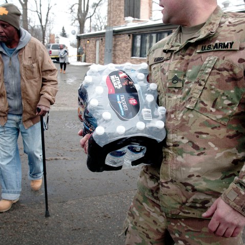 Michigan National Guard Staff Sergeant Steve Kiger helps a Flint resident take bottled water out to his car after he received it at a Fire Station in Flint, Mich., Jan. 13, 2016. (Photo by Bill Pugliano/Getty)