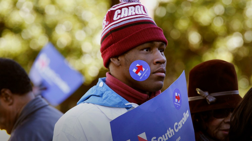 An attendee decked in Hillary Clinton campaign merchandise listens during an event on the front steps of the State House in Columbia, S.C., Jan. 18, 2016. (Photo by Patrick T. Fallon/Bloomberg/Getty)
