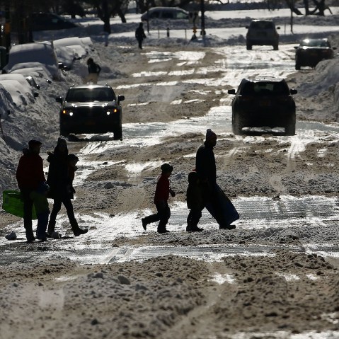 People cross a snow covered street on a sunny day following a blizzard on Jan. 24, 2016 in the Brooklyn borough of New York City. (Photo by Spencer Platt/Getty)