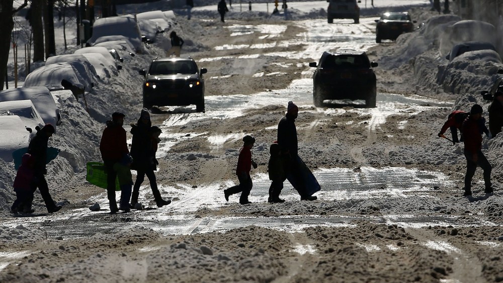 People cross a snow covered street on a sunny day following a blizzard on Jan. 24, 2016 in the Brooklyn borough of New York City. (Photo by Spencer Platt/Getty)