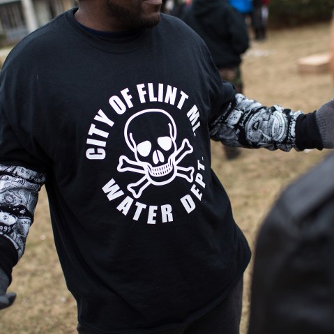 A shirt worn by a man during a rally displays a poisonous logo alongside the text 'City of Flint MI Water Dept.' on Jan. 24, 2016 at Flint City Hall in Flint, Mich. (Photo by Brett Carlsen/Getty)