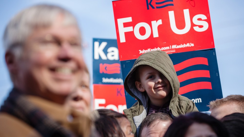 A child listens to Republican presidential candidate John Kasich speak to campaign workers and volunteers outside his campaign headquarters in Manchester, N.H., Feb. 6, 2016. (Photo by Matthew Cavanaugh/Getty)