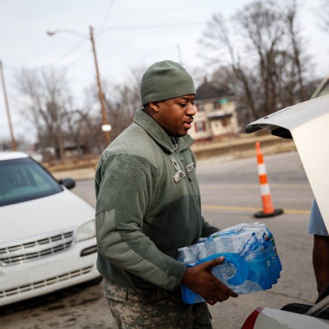 Army National Guard Spc. Terence Burse carries bottled water out to the car for a resident on Feb. 7, 2016 in Flint, Mich. (Photo by Sarah Rice/Getty)