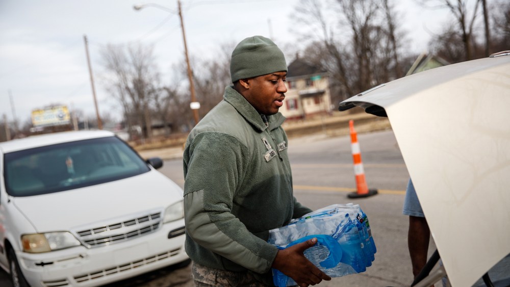 Army National Guard Spc. Terence Burse carries bottled water out to the car for a resident on Feb. 7, 2016 in Flint, Mich. (Photo by Sarah Rice/Getty)