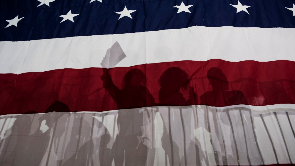 Supporters for Democratic presidential candidate Hillary Clinton are silhouetted in a large American flag at a rally following Super Tuesday on March 2, 2016 in New York City. (Photo by Andrew Renneisen/Getty)