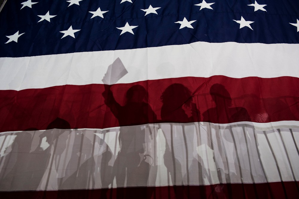Supporters for Democratic presidential candidate Hillary Clinton are silhouetted in a large American flag at a rally following Super Tuesday on March 2, 2016 in New York City. (Photo by Andrew Renneisen/Getty)