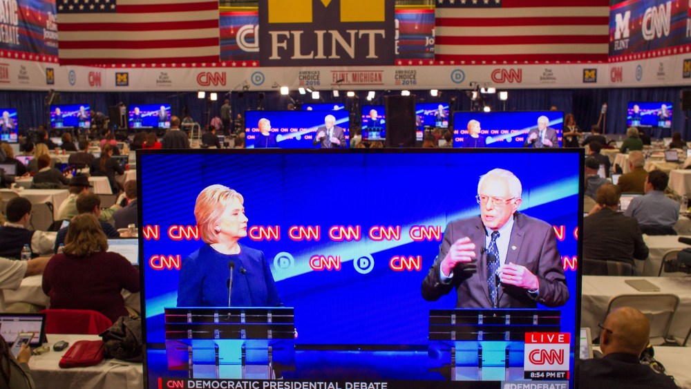 Journalists watch Democratic presidential candidates Hillary Clinton and Bernie Sanders debate on televisions in the media room at the University of Michigan in Flint, Mich. on March 6, 2016. (Photo by Geoff Robins/AFP/Getty)