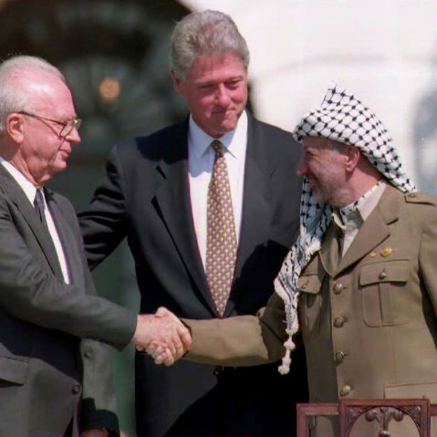 US President Bill Clinton stands between PLO leader Yasser Arafat and Israeli Prime Minister Yitzahk Rabin as they shake hands on Sep. 13, 1993 at the White House in Washington DC. (Photo by J. David Ake/AFP/Getty)