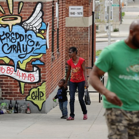 Neighbors walk past the spot where Baltimore police arrested Freddie Gray at the Gilmor Homes in the Sandtown neighborhood one year after Gray died April 19, 2016 in Baltimore, Md. (Photo by Chip Somodevilla/Getty)