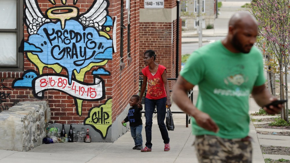 Neighbors walk past the spot where Baltimore police arrested Freddie Gray at the Gilmor Homes in the Sandtown neighborhood one year after Gray died April 19, 2016 in Baltimore, Md. (Photo by Chip Somodevilla/Getty)