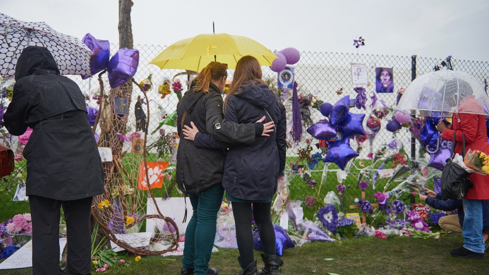 Two Prince fans embrace in front of the memorial outside Paisley Park on April 24, 2016 in Chanhassen, Minn. (Photo by Jules Ameel/Getty)